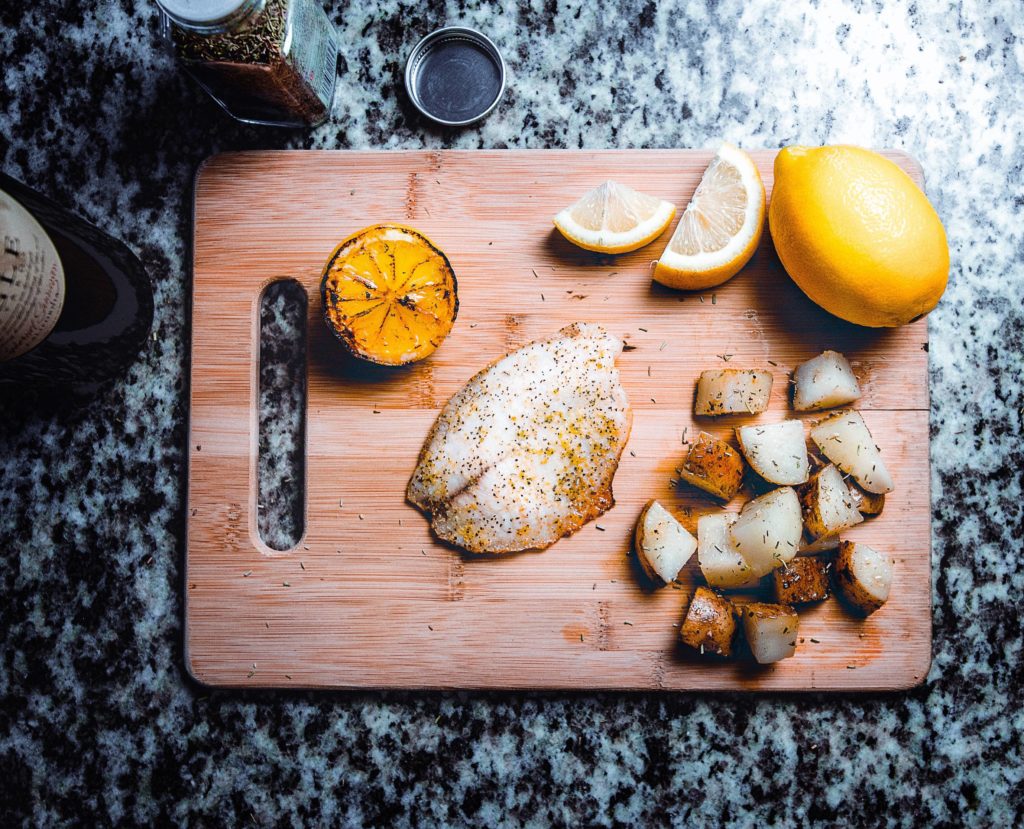 fish fillet and lemon on a chopping board