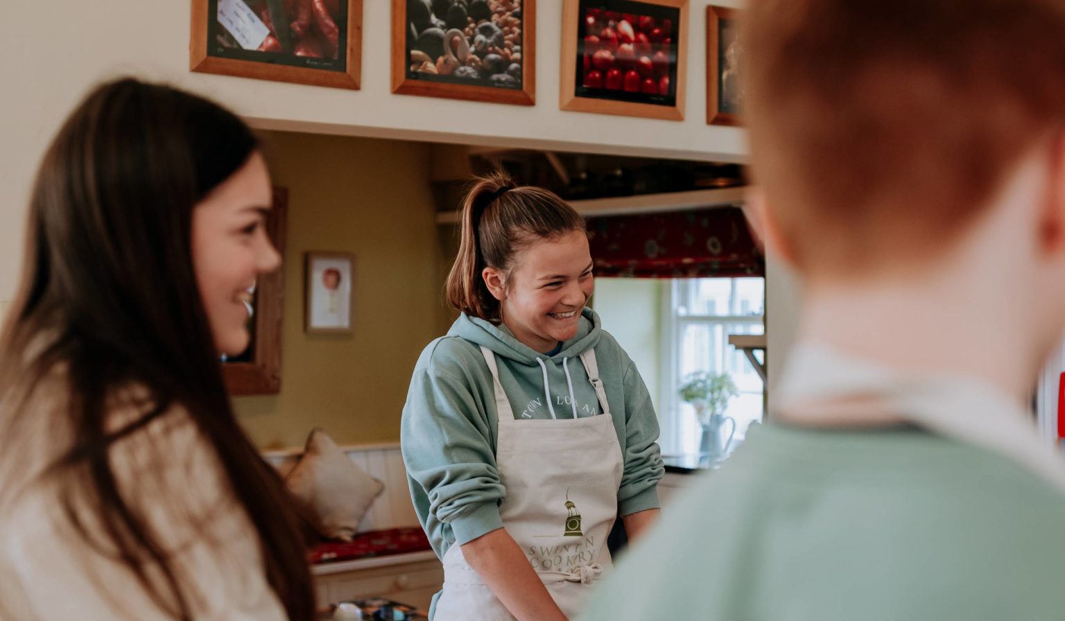 Smiling teenagers wearing aprons as they take part in a junior cooking course at Swinton Cookery School near Harrogate and Ripon in North Yorkshire