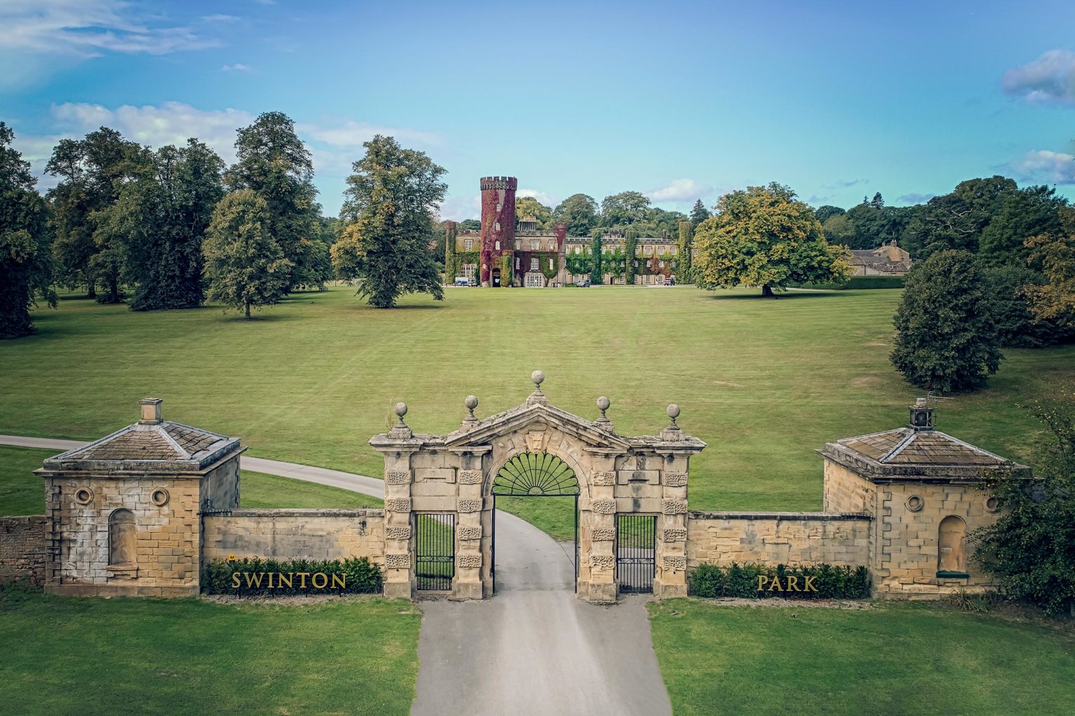 Exterior photo of Swinton Park luxury castle hotel and spa near Harrogate and the Yorkshire Dales, featuring the front grass lawn and helicopter pad area