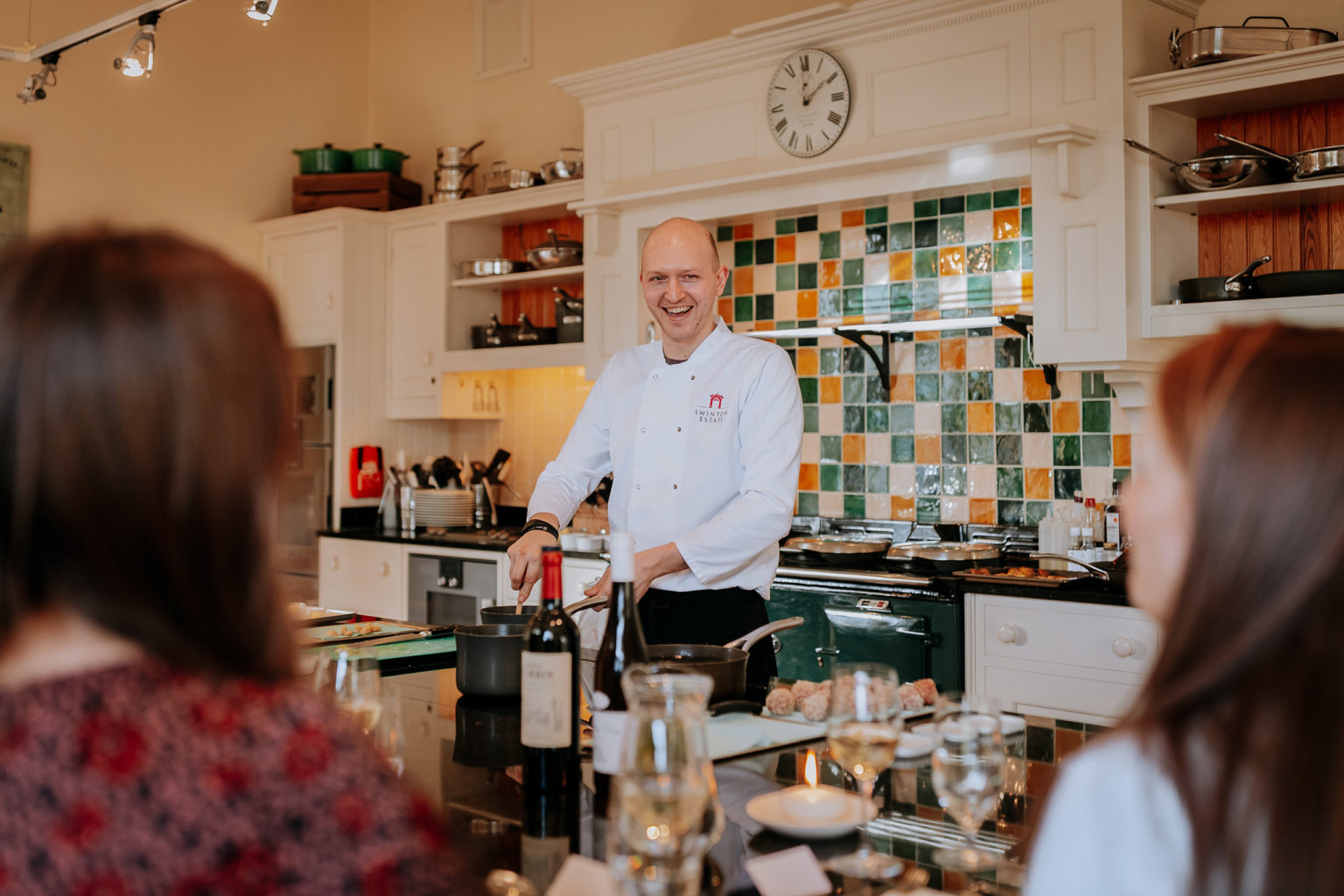 A smiling chef cooks in front of guests at Swinton Cookery School's Chef's Table