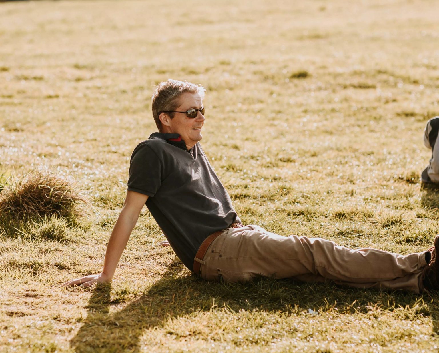 A man relaxing on meadow grass at Swinton Bivouac in North Yorkshire