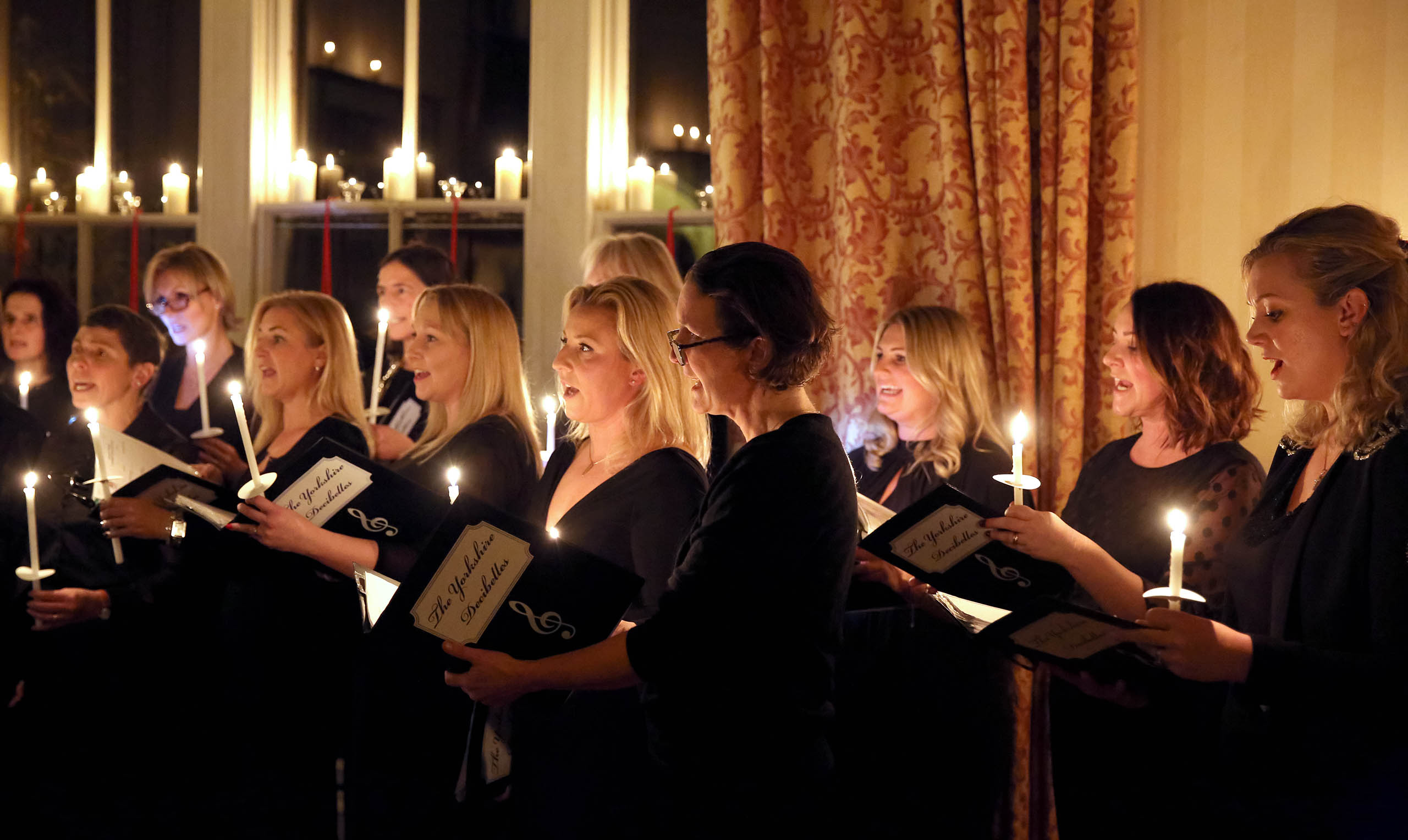 A choir singing in candlelight during a charity event at Swinton Park Hotel in North Yorkshire