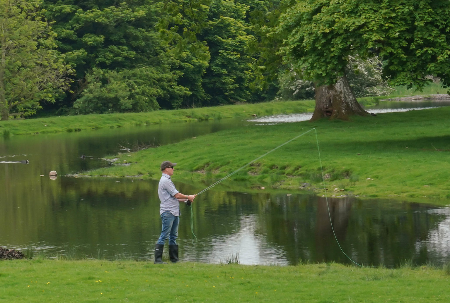 A man fishing on a lake at Swinton Park Hotel near Harrogate and Ripon in North Yorkshire.