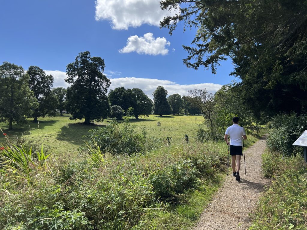 A man Nordic walking next to trees in the Parkland and Gardens on the Swinton Estate in North Yorkshire