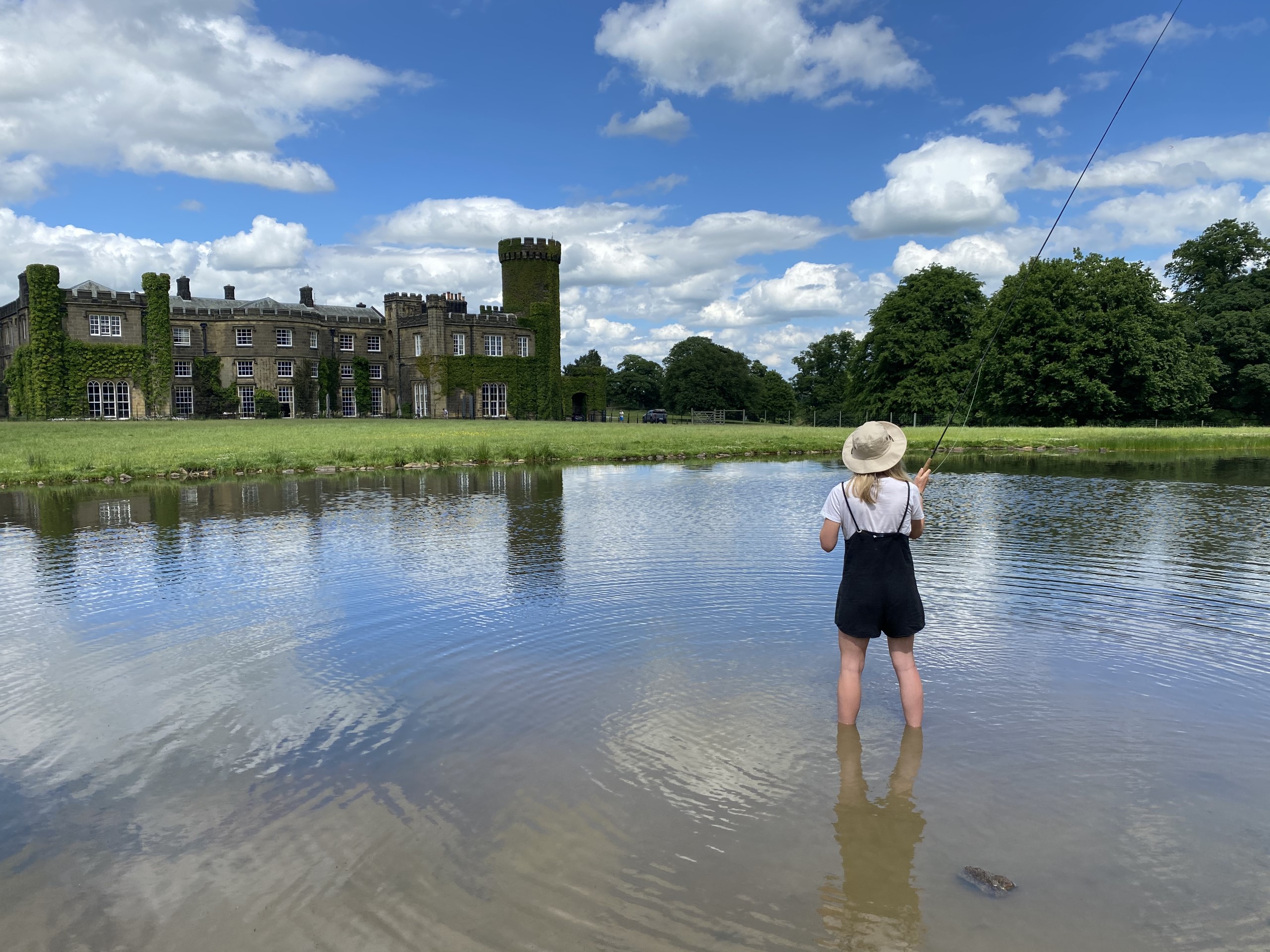 A woman fishing in a lake in front of Swinton Park Hotel in North Yorkshire