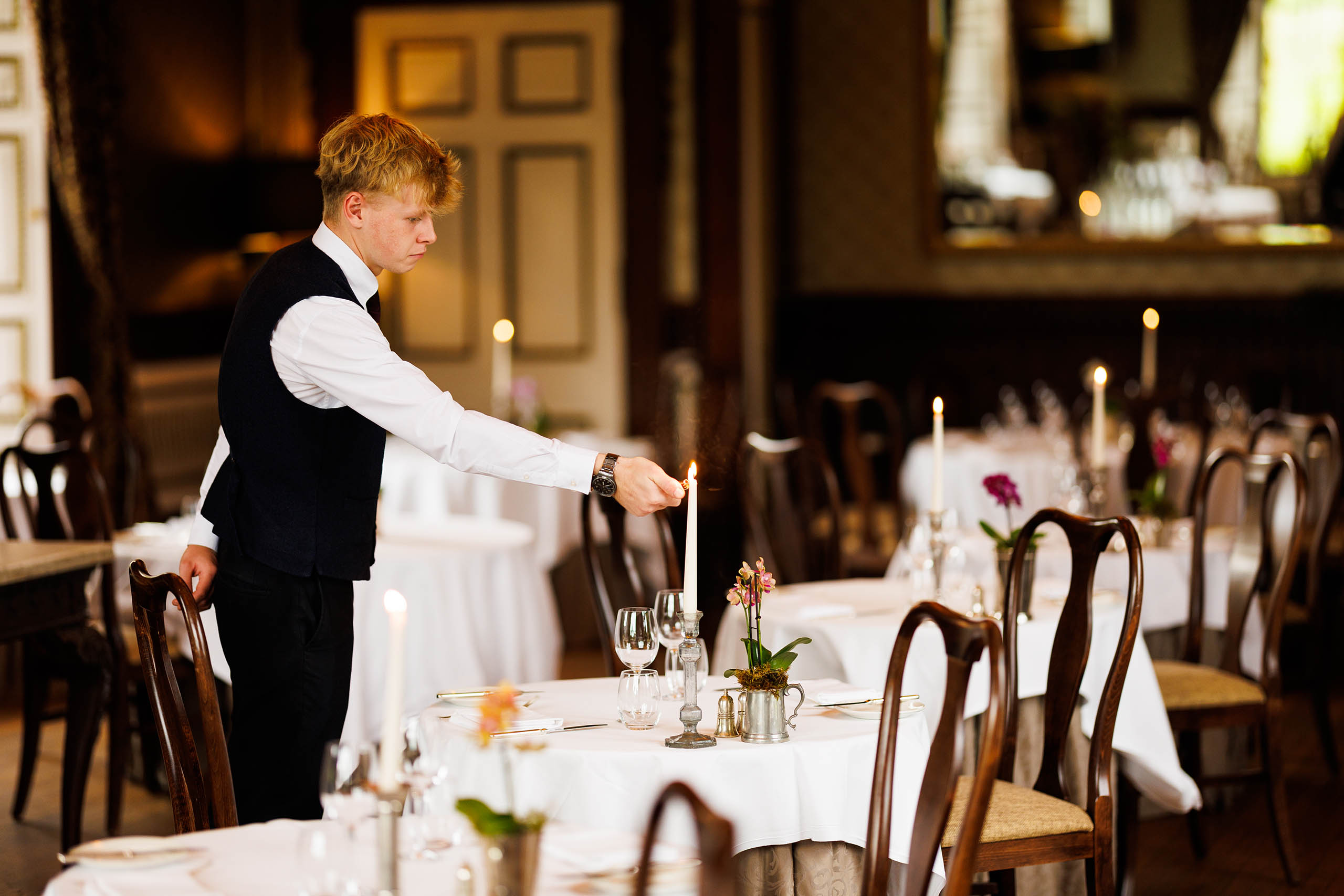 A man lighting romantic candles in Samuel's Restaurant on the Swinton Estate in North Yorkshire