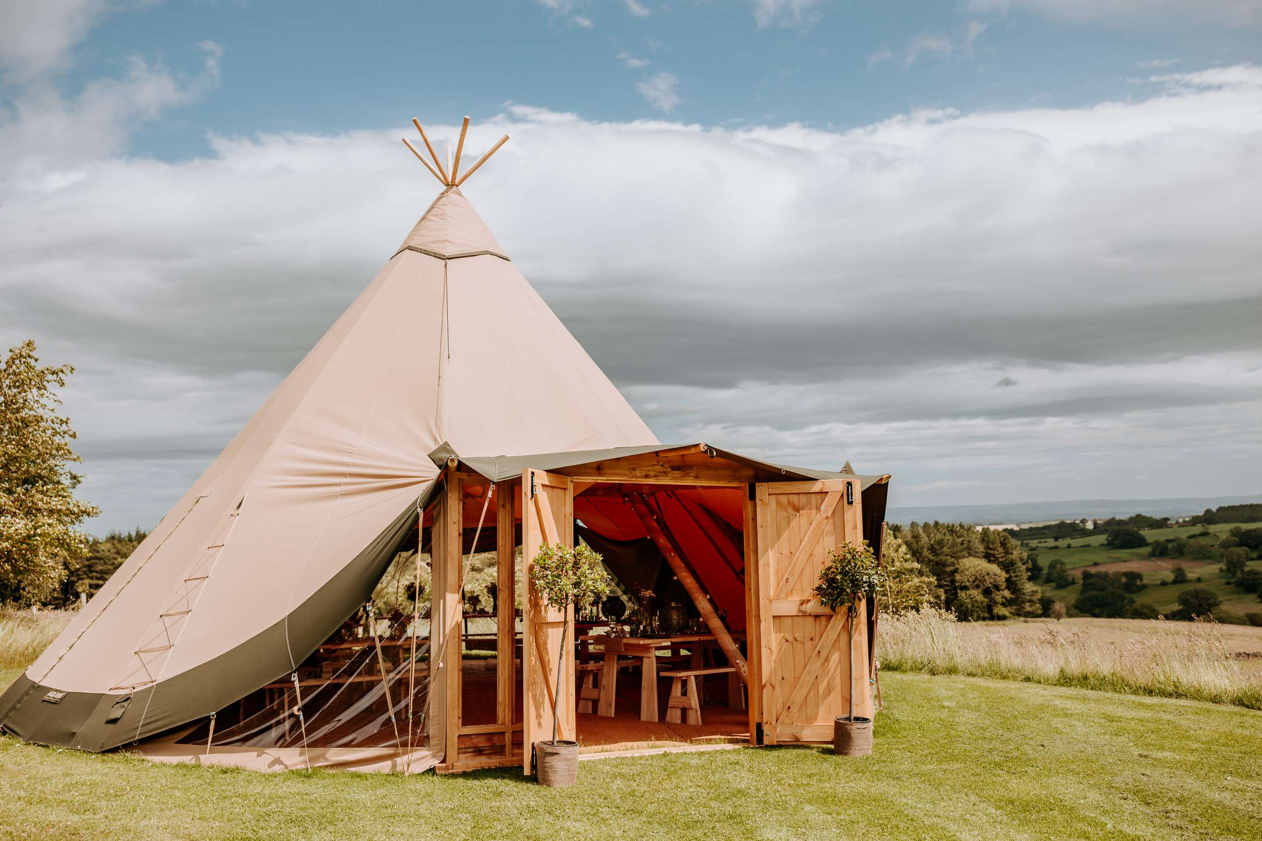 An outdoor tipi on a grassy meadow at Swinton Bivouac in North Yorkshire