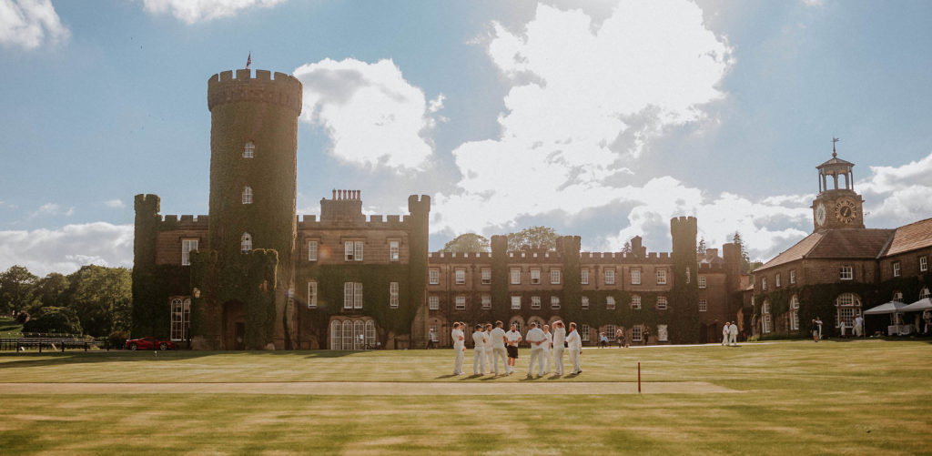 A game of cricket being played in front of Swinton Park castle hotel near Harrogate and Ripon in North Yorkshire