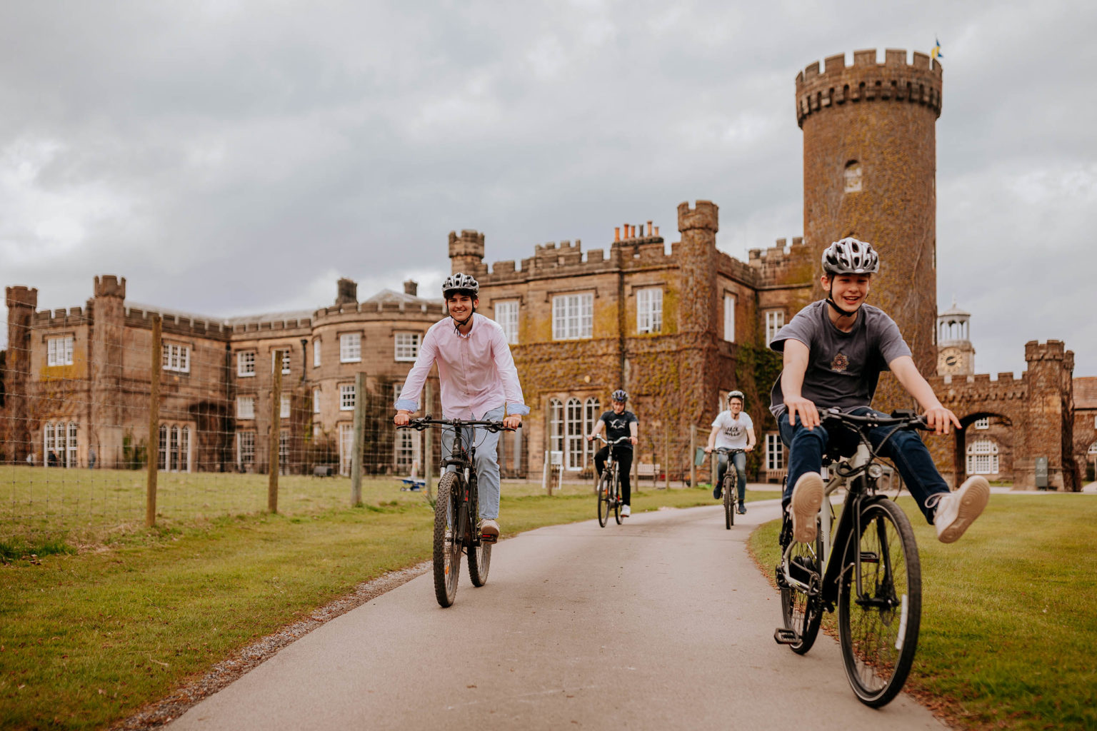 Teenagers cycling on hire bikes in front of Swinton Park Hotel in North Yorkshire