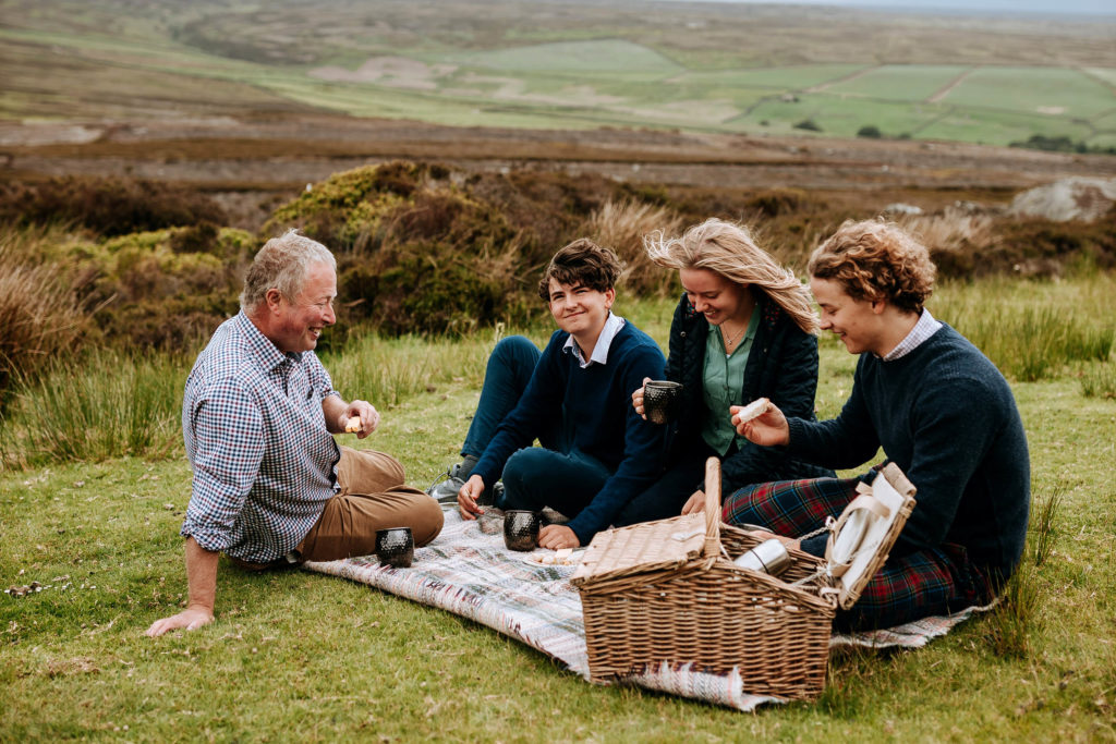 A family eating a picnic on the grass in the Yorkshire countryside on the Swinton Estate