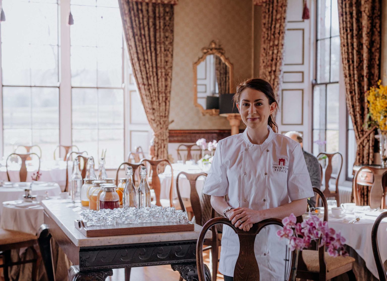 Chef Ruth Hansom standing among the tables and chairs in the fine dining Samuel's Restaurant on the Swinton Estate in North Yorkshire