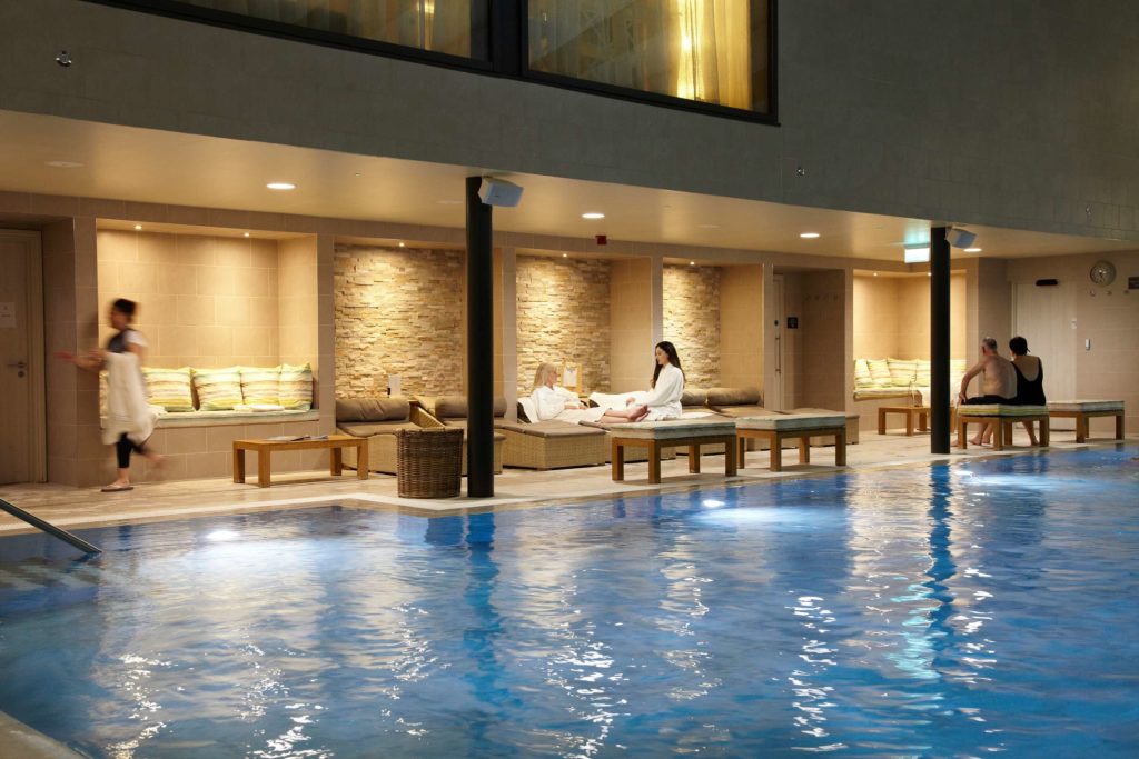 Spa day guests relaxing next to the swimming pool during the evening at Swinton Country Club and Spa in North Yorkshire