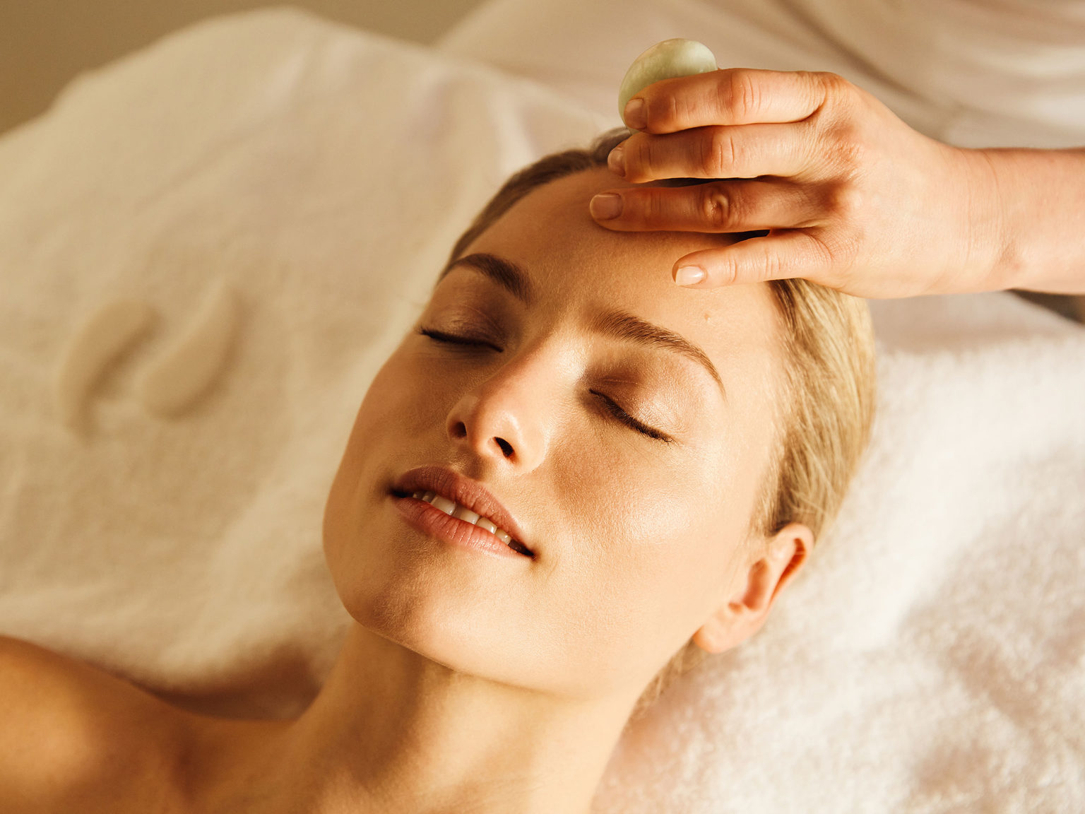 A woman having a facial with jade stones during a relaxing spa day