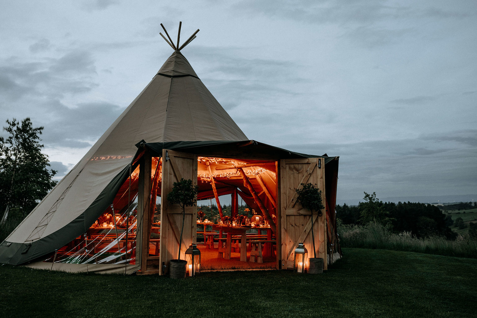 Exterior of a tipi at night, illuminated by candles for a celebration event, at Swinton Bivouac in North Yorkshire