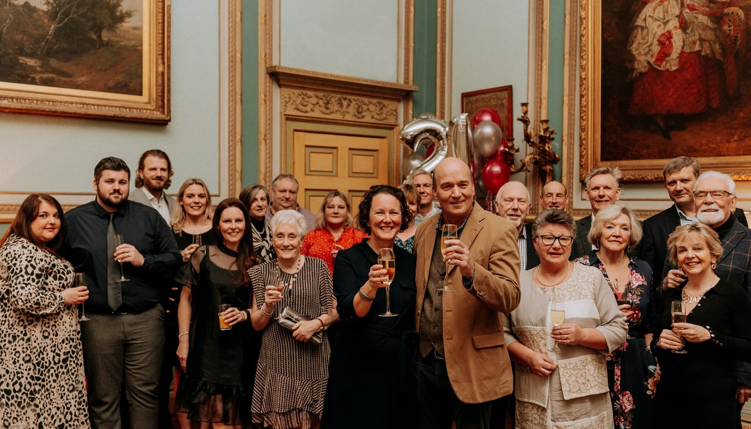 A group of people holding up glasses of champagne, with Mark and Felicity Cunliffe-Lister in front, during a charity event at Swinton Park Hotel