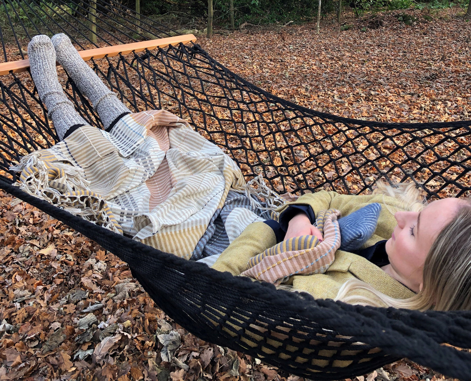 A woman lying in a woodland hammock in the wellbeing space at Swinton Country Club in North Yorkshire.