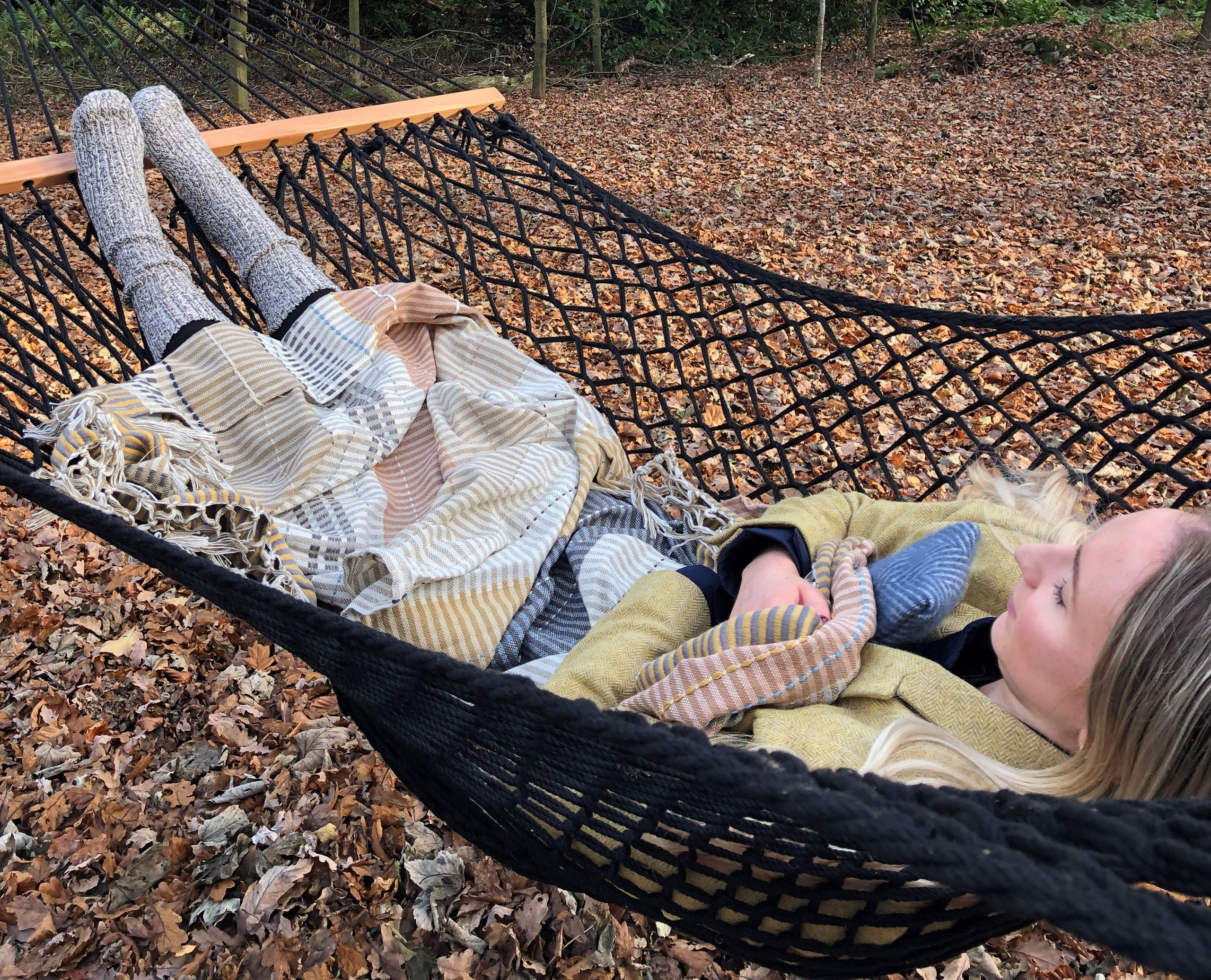 A woman lying in a woodland hammock in the wellbeing space at Swinton Country Club in North Yorkshire.